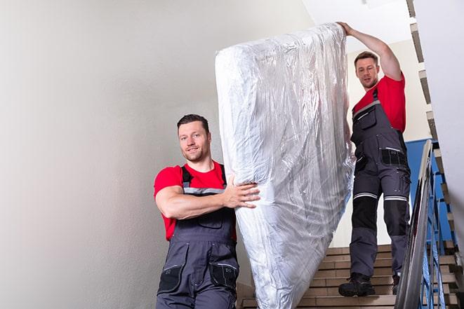 two people carrying a box spring down a staircase in Bonner Springs, KS